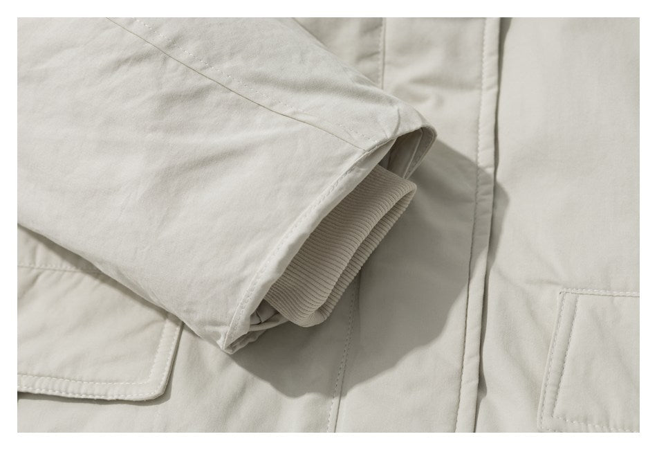 Close-up of an off-white jacket sleeve with a ribbed cuff and stitched pocket details.