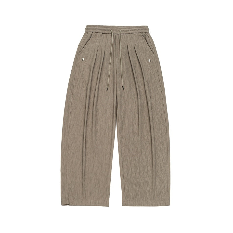 Khaki wide-leg drawstring pants with front pleats, side pockets and a textured fabric, flat lay front view