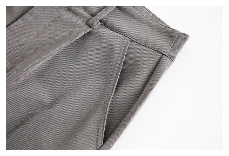 Close-up of gray trouser fabric, waistband, belt loop, and angled front pocket opening.