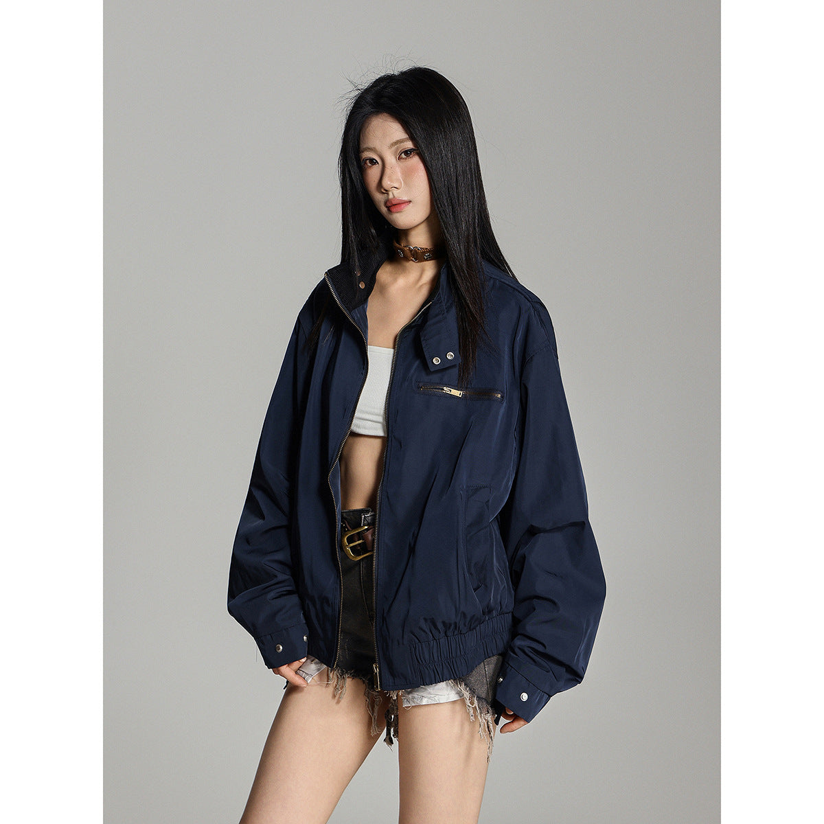 Model wearing an open navy jacket with a zip chest pocket, snap collar, and gathered hem.