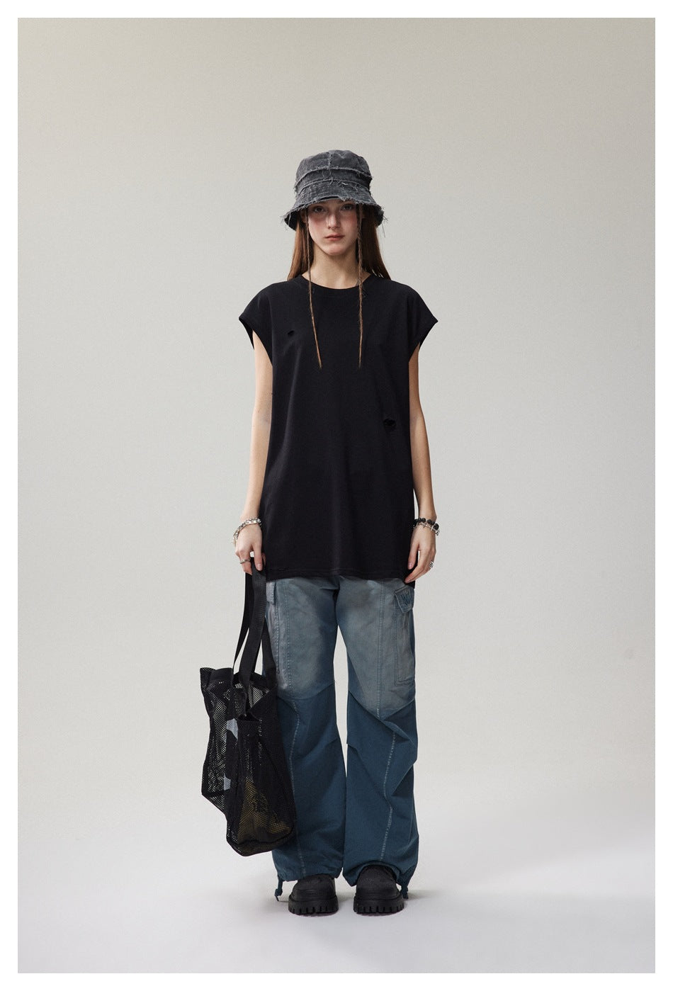 Model wearing a loose black cap-sleeve T-shirt with small distressed slits, shown from the front.