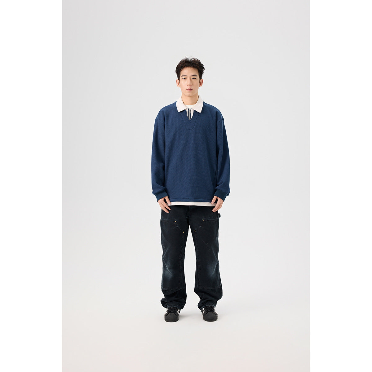 Front view of a model wearing a navy pullover with a white collar and short zip placket.