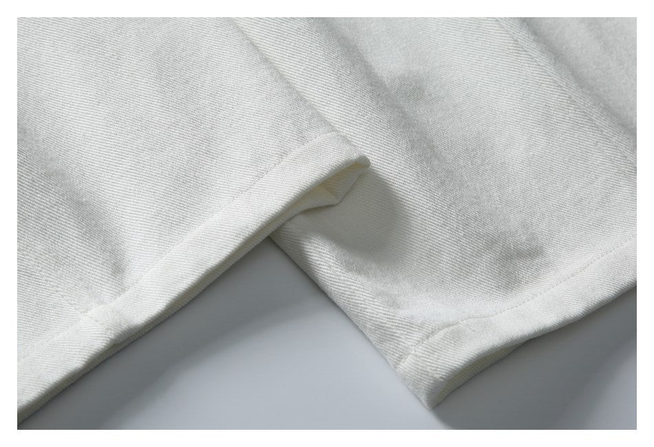 Close-up of the stitched hem and folded edge of white trousers.