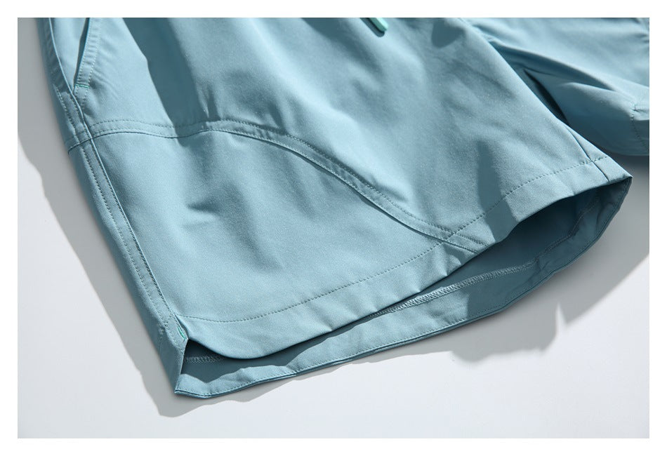 Close-up of the curved stitched hem and side seam on light blue shorts.