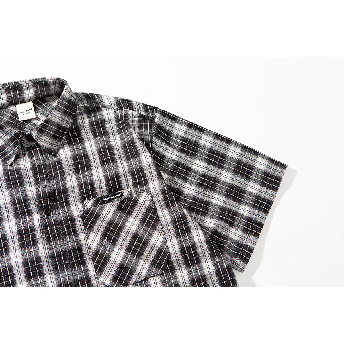 Angled close-up of the plaid shirt's short sleeve, shoulder, collar, and chest pocket.