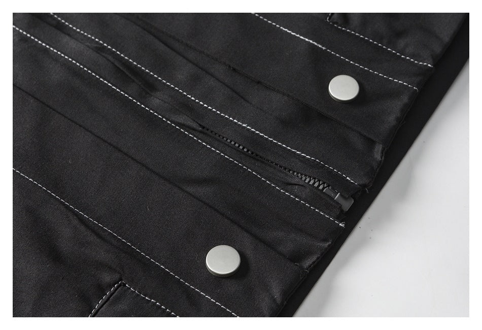 Close-up of a black garment with a zipper and two round silver snaps, outlined by white stitching.