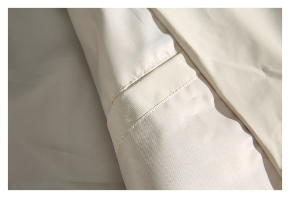 Close-up of cream fabric showing a folded seam and parallel rows of stitching.