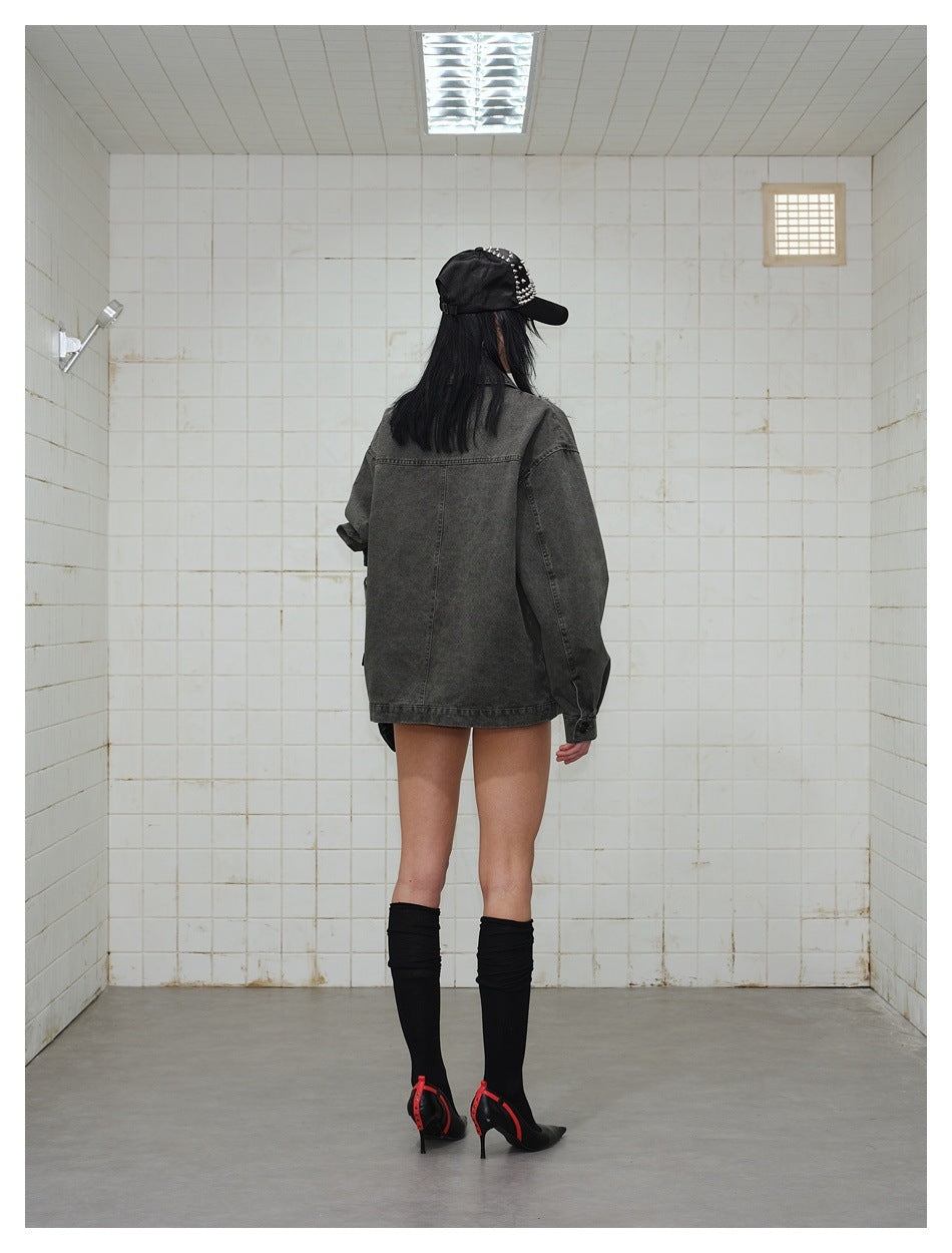 Back view of a model wearing an oversized charcoal gray jacket with a yoke seam and long sleeves.