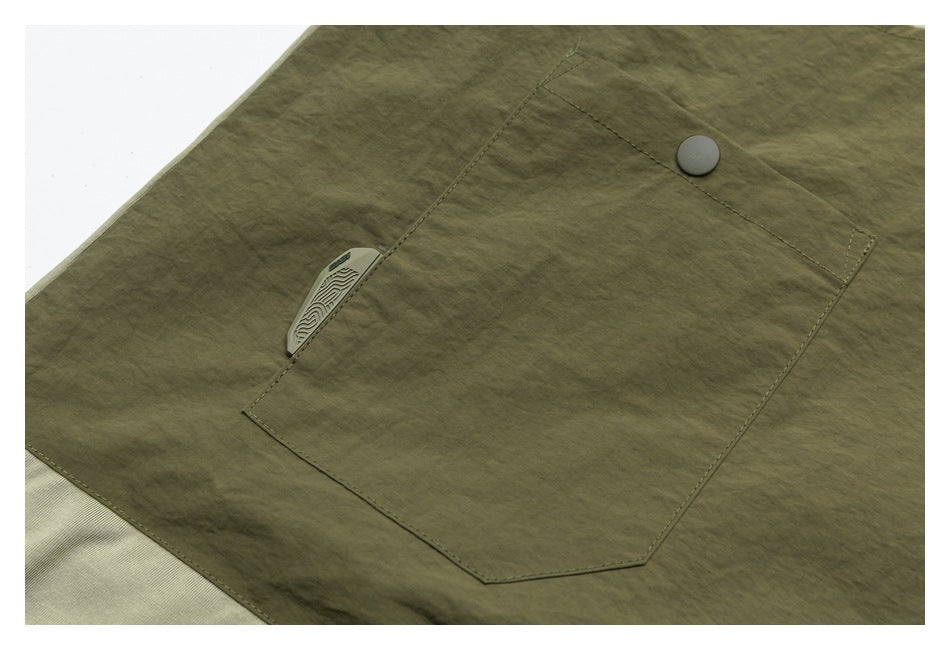 Close-up of an olive-green garment pocket with a round button and a small patterned tab.