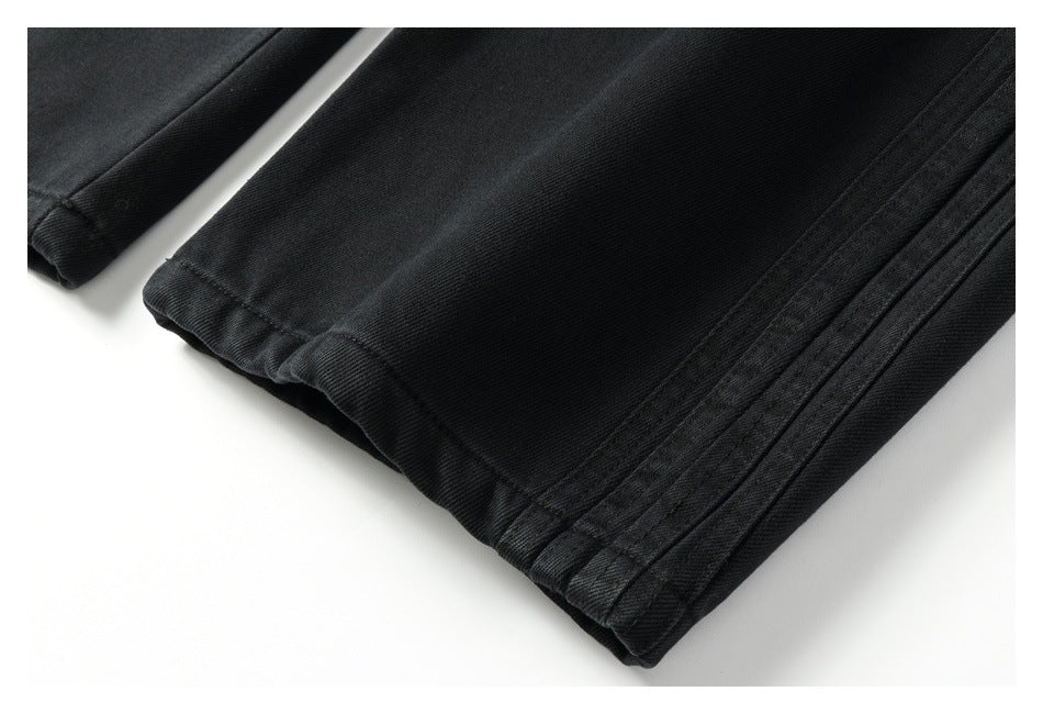 Close-up of a black pants leg hem and parallel side stitching.