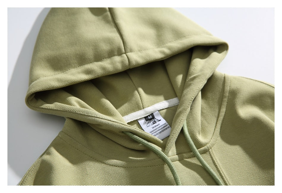 Close-up of the olive-green hood and neckline, with drawstrings and an interior size label.