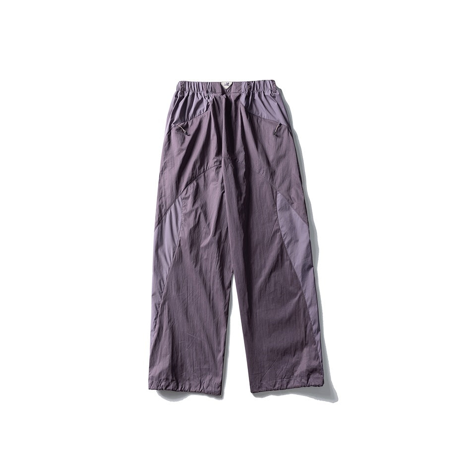 Muted purple wide-leg pants with lighter purple contrast panels, elastic waist and zip pockets, flat lay back view