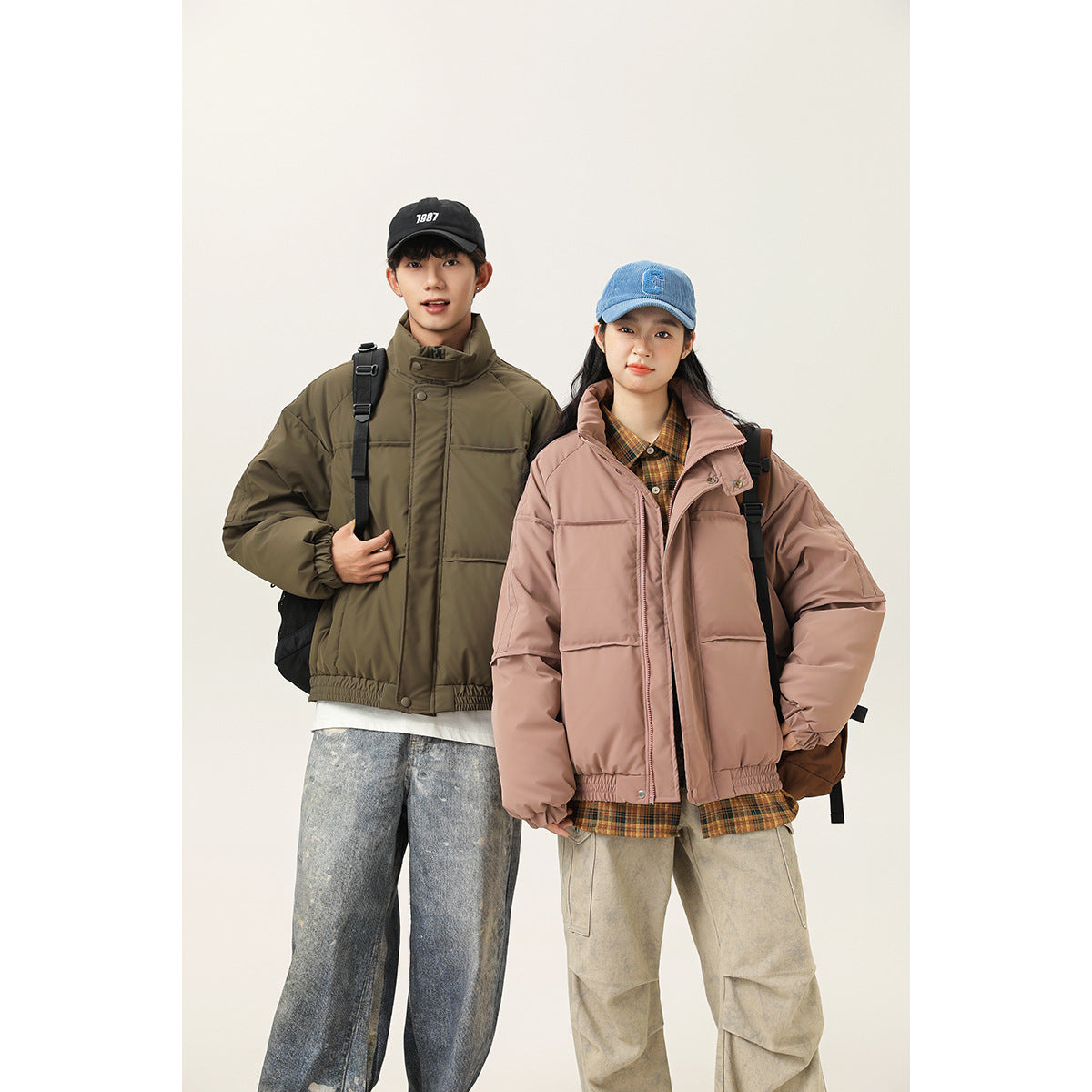 Two models wear oversized zip-front jackets: olive green on the man and dusty rose on the woman.