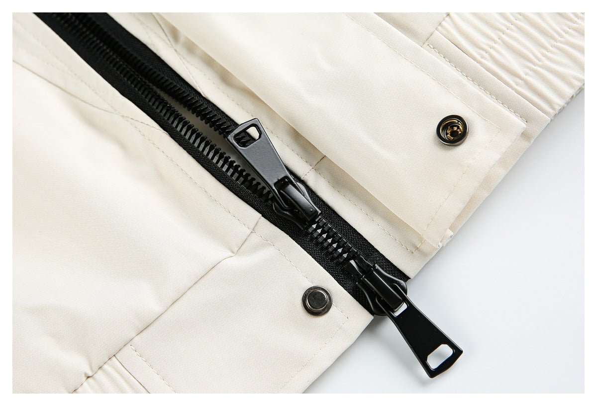 Close-up of a black two-way zipper and snap fasteners on a cream garment.