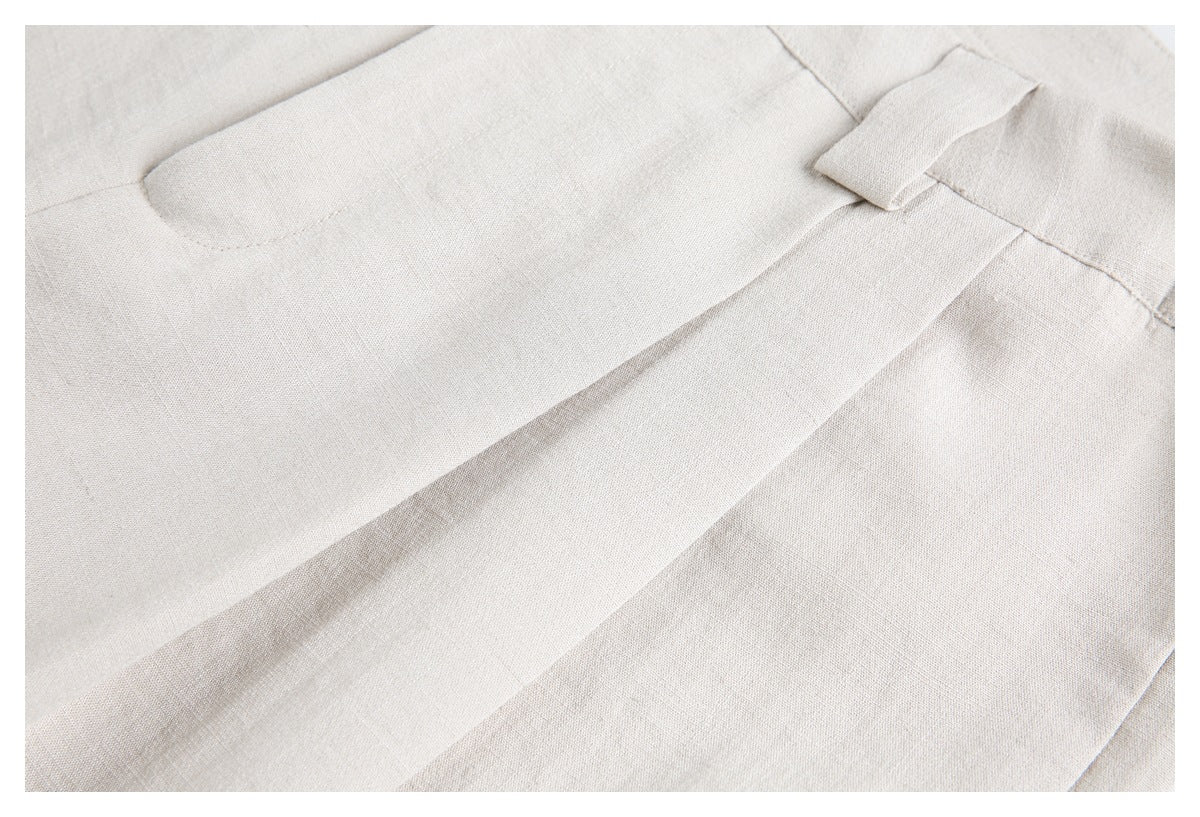 Close-up of ivory trousers showing a rear welt pocket and a front pleat.