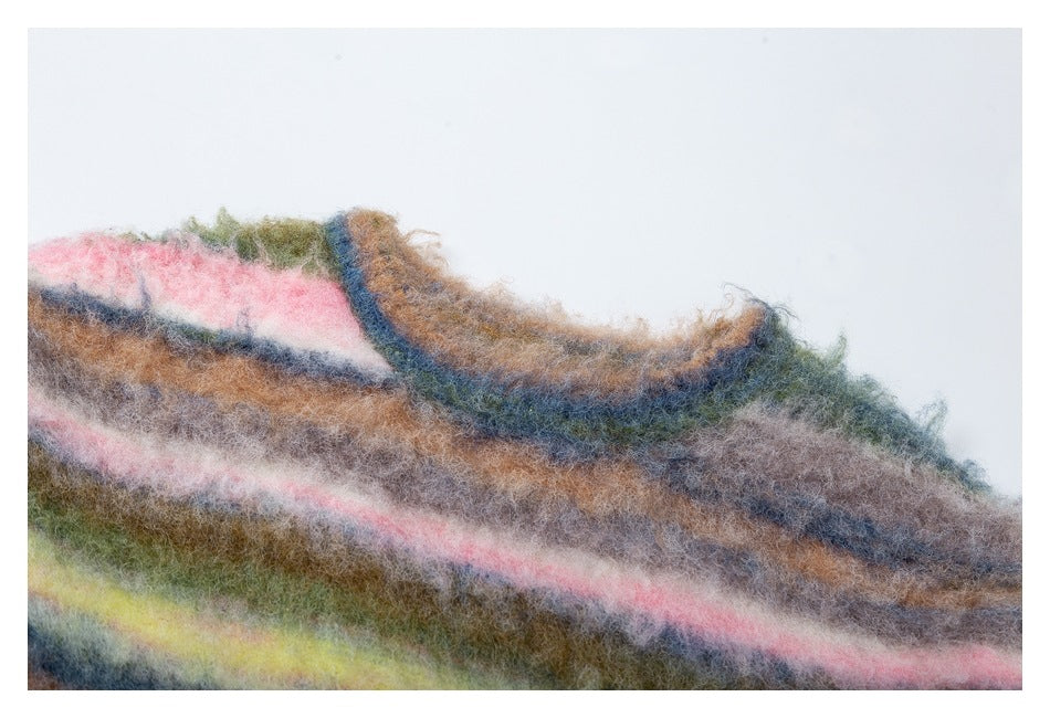 Close-up of the fuzzy multicolored striped sweater's crew neckline and knit surface.