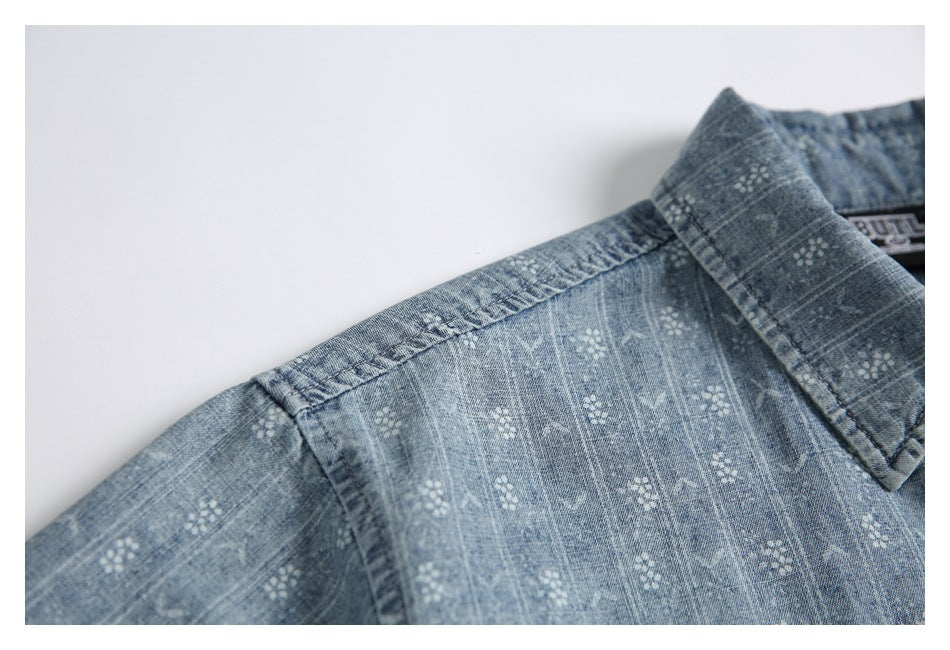 Close-up of the blue patterned shirt's collar and shoulder seam on a white background.