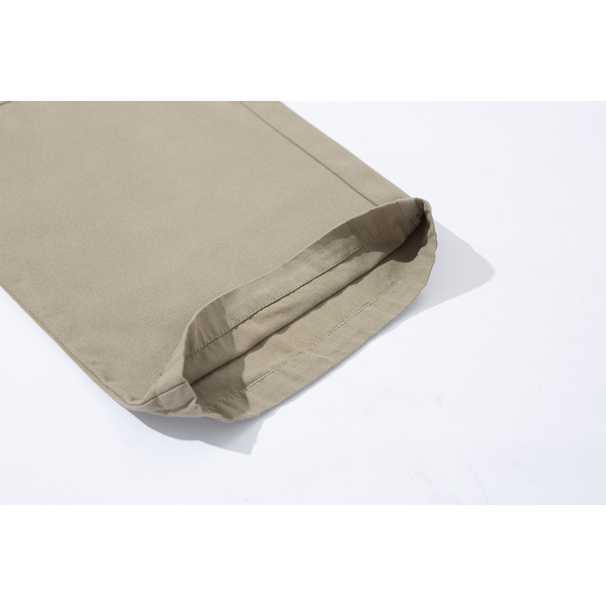 Close-up of the stitched hem at the bottom of a beige trouser leg.