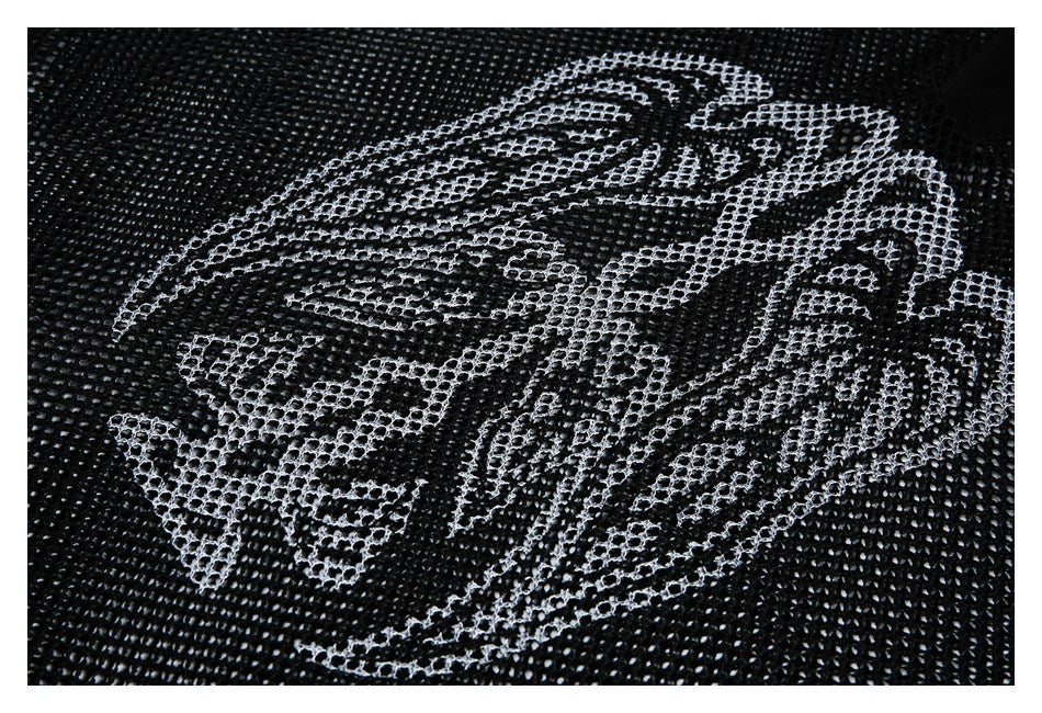 Close-up of a large pale abstract graphic printed across black open-knit fabric.