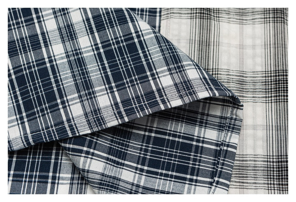 Close-up of overlapping folds in navy-and-white plaid fabric beside gray-and-black plaid fabric.