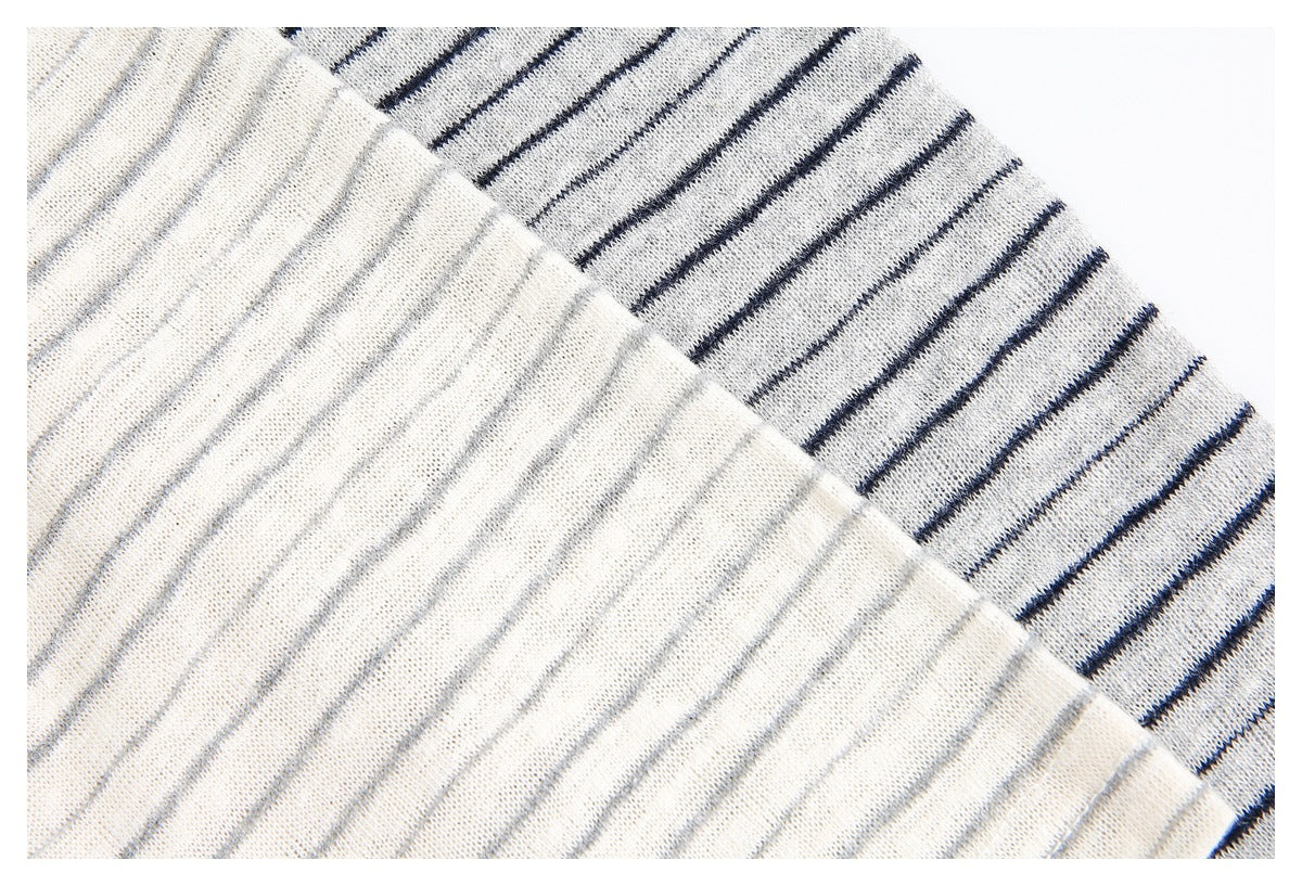 Close-up of light gray knit fabric with thin navy stripes, shown folded to reveal its texture.
