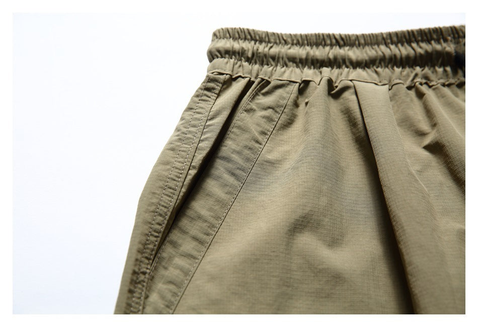 Close-up of the olive-khaki shorts' elastic waistband and side pocket seam.