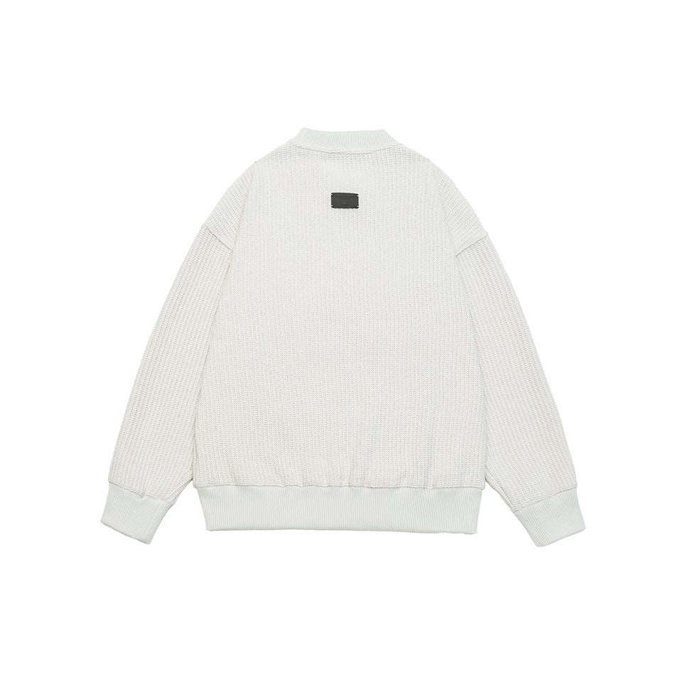Back view of a white textured crewneck sweatshirt laid flat, with ribbed cuffs and hem and a small dark label below the