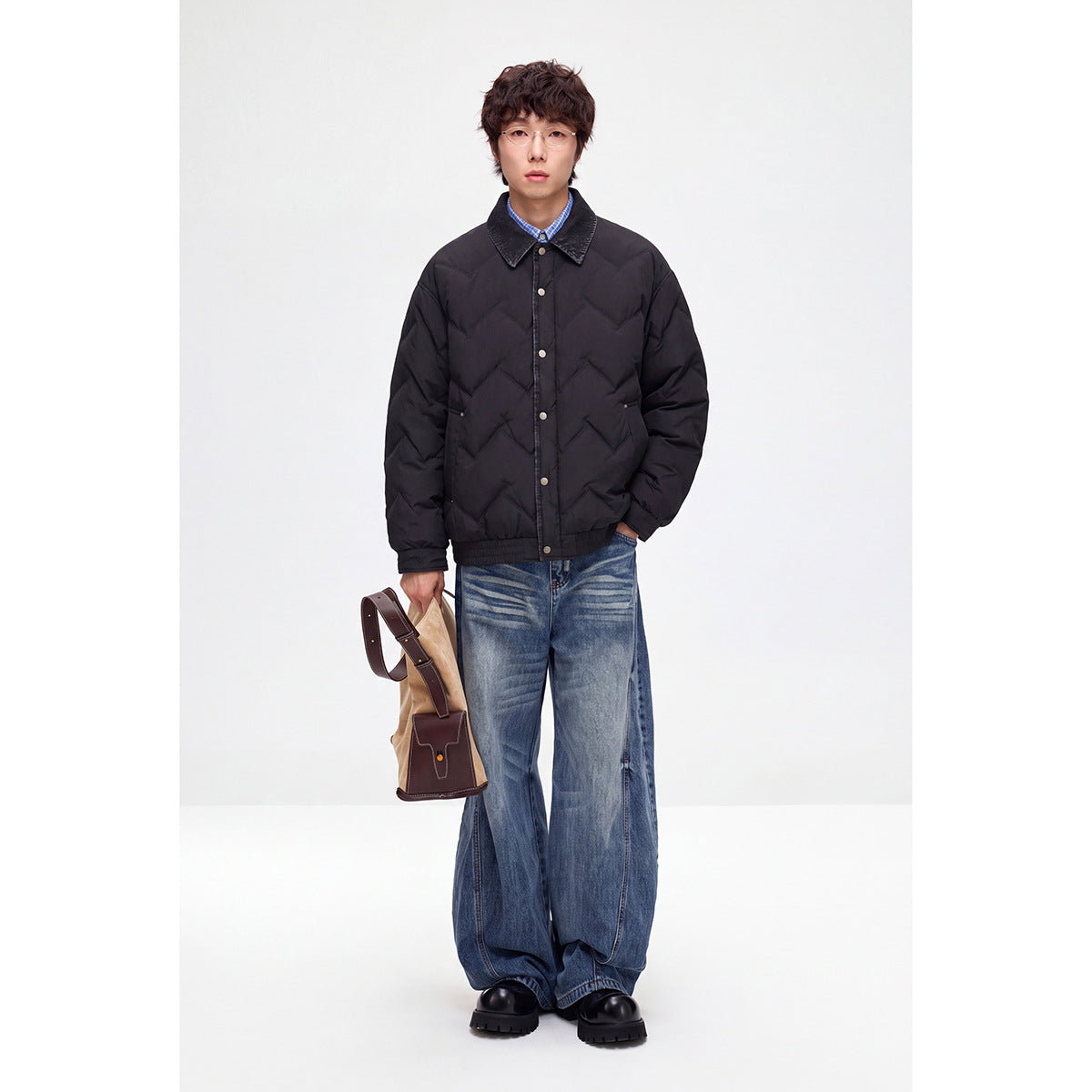Front view of a model wearing a black chevron-quilted jacket with a dark collar and snap closure.