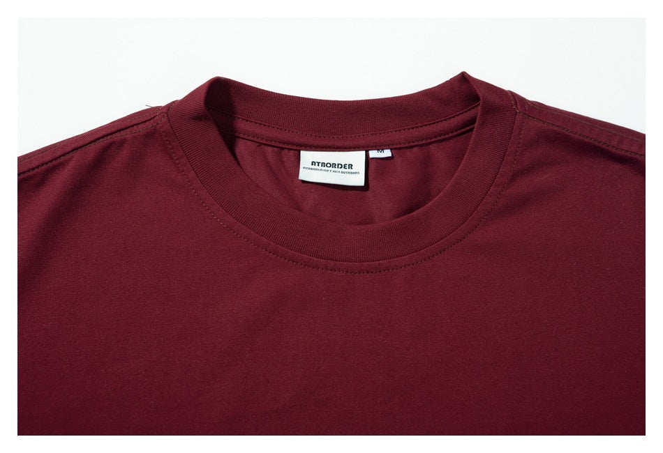 Close-up of the burgundy T-shirt's ribbed crew neck and sewn-in brand and size labels.
