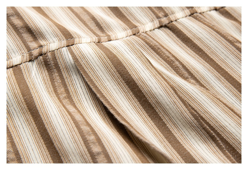 Close-up of tan, brown, and cream striped fabric with a stitched seam and gathered folds.