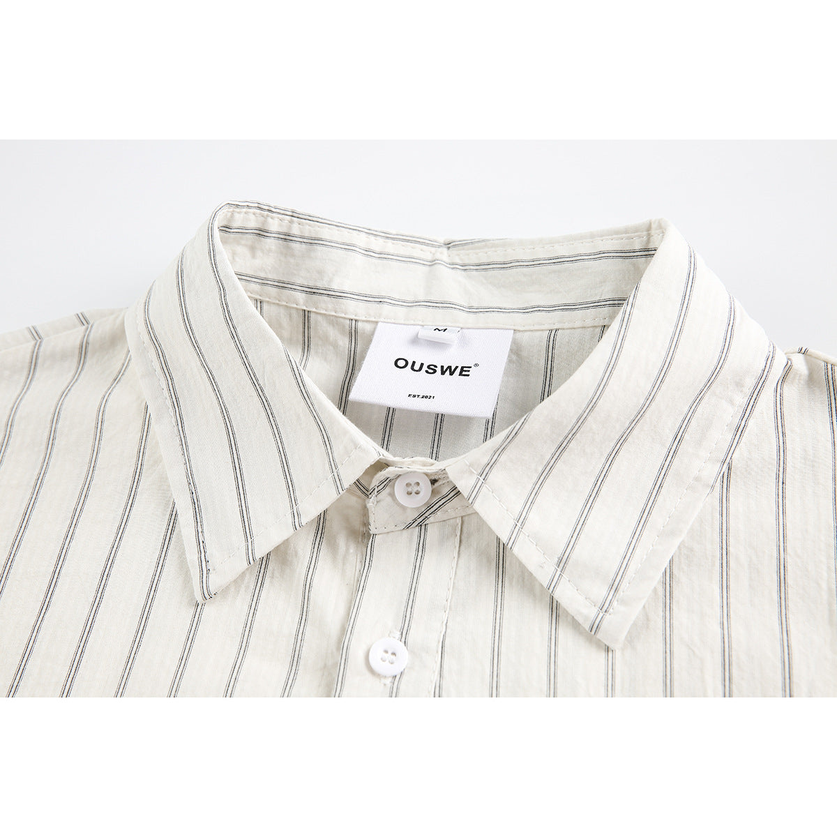 Close-up of an off-white shirt collar with thin dark vertical stripes and white buttons.