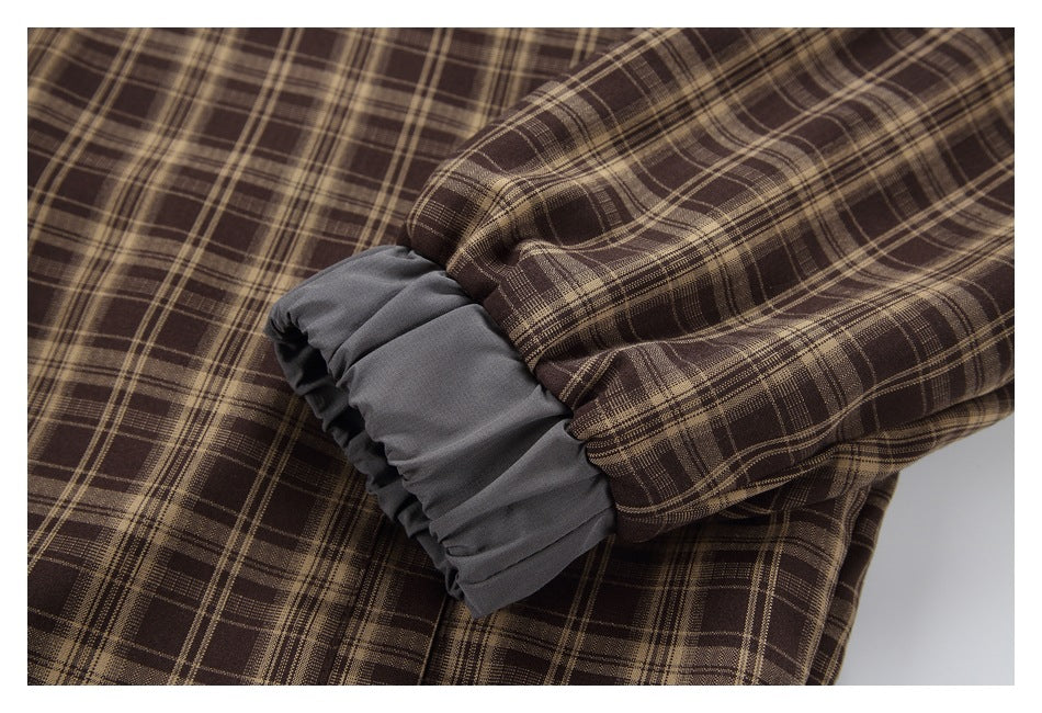 Close-up of a gathered gray cuff at the end of a brown plaid sleeve.