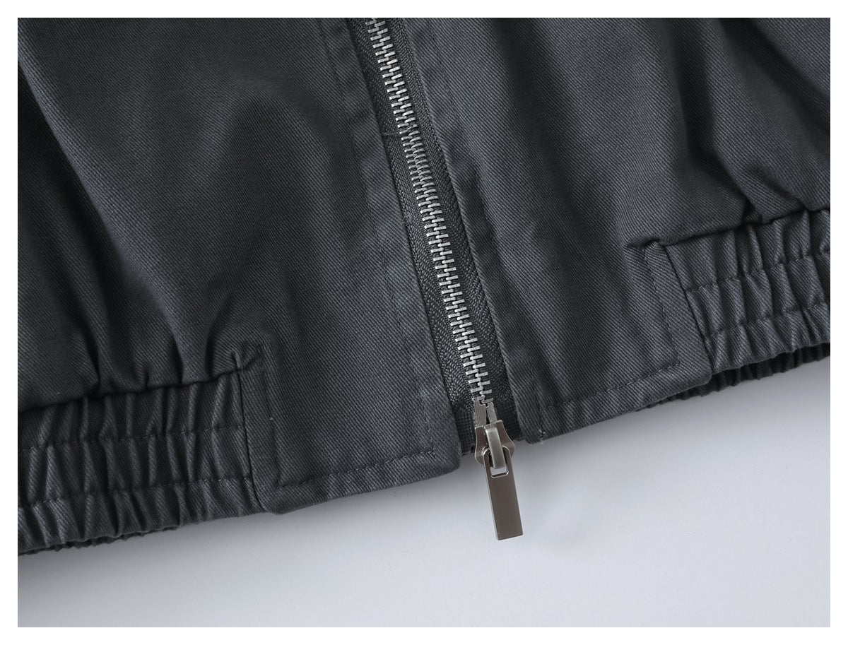 Close-up of the charcoal jacket’s front zipper and gathered elastic hem.