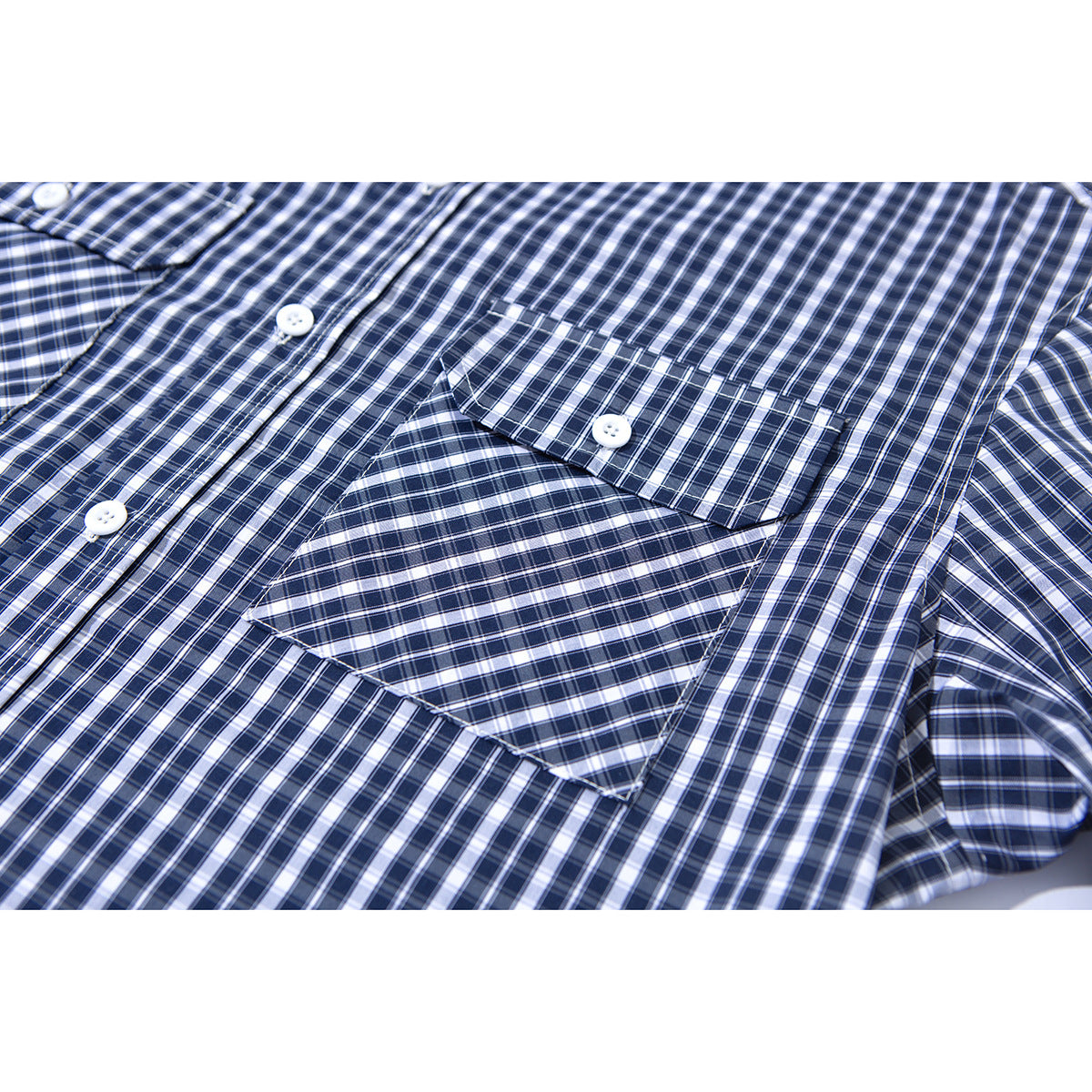 Close-up of a navy and white checked shirt showing a chest pocket with a buttoned flap.