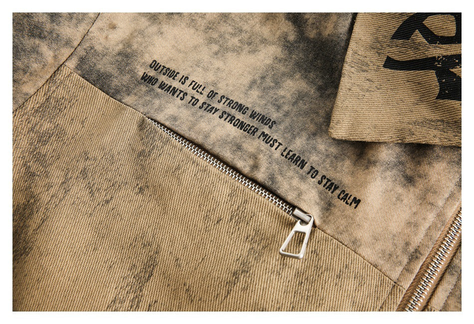 Close-up of a tan mottled jacket showing a black English quote printed above a diagonal metal zipper.
