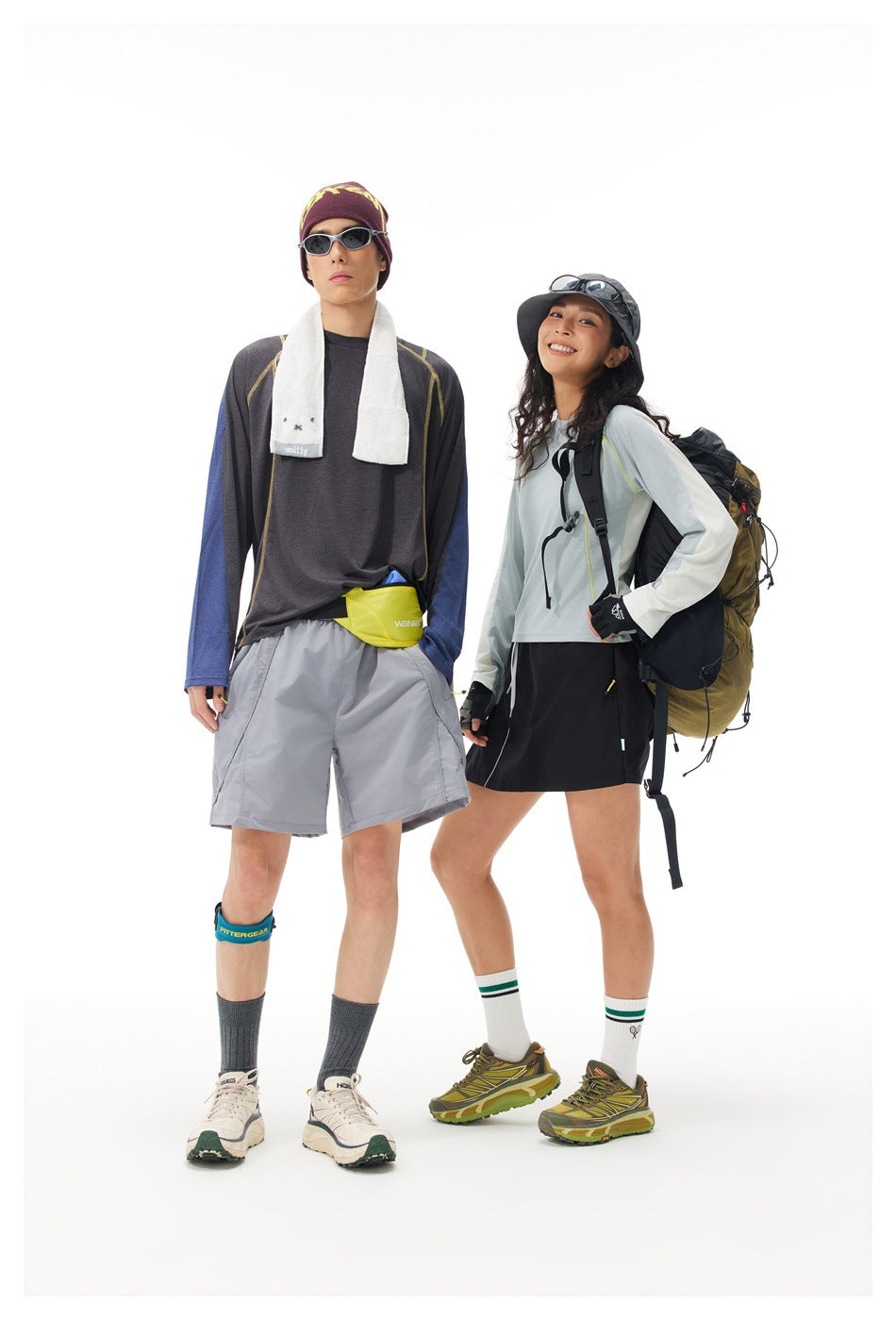 Two models pose in outdoor outfits: a man in a charcoal and blue top with gray shorts, and a woman in a pale blue top and