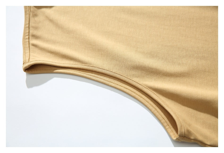 Close-up of the sand-colored shirt's bound armhole edge and stitching.