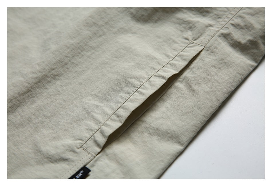 Close-up of a narrow opening along a stitched seam on the light beige shirt.