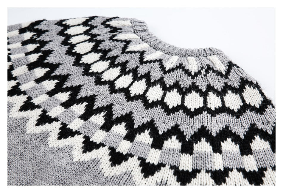 Close-up of a gray sweater neckline and upper chest with a black and white geometric knit pattern.
