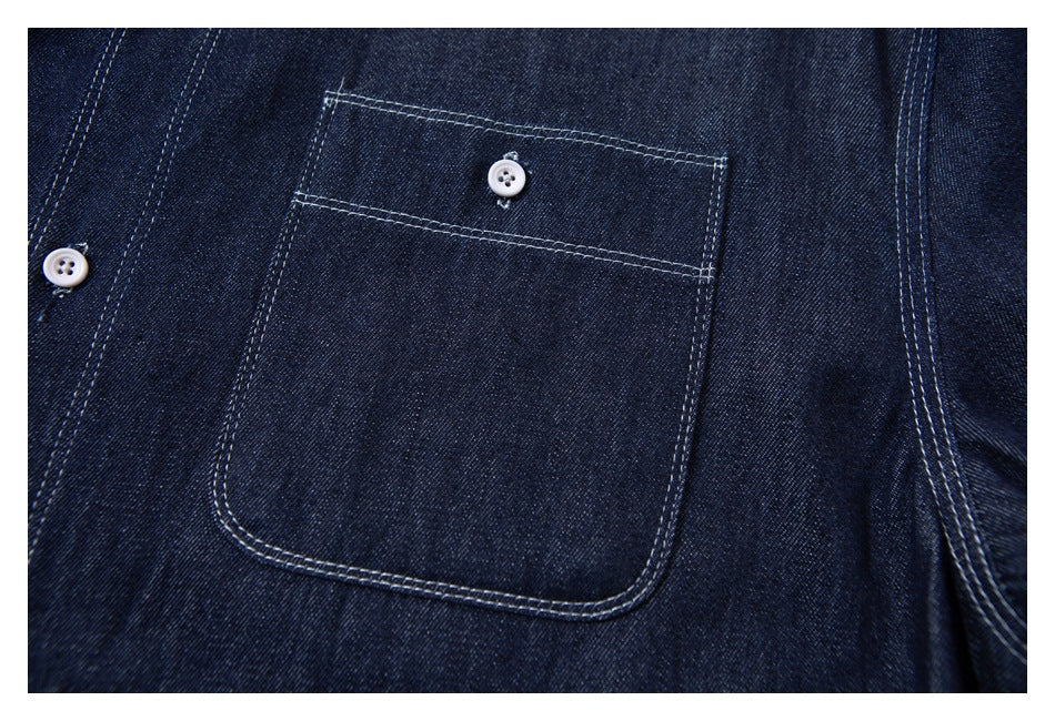 Close-up of dark indigo denim with a large stitched pocket and small white buttons.