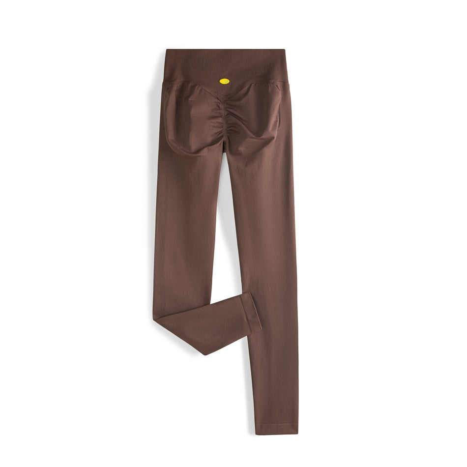 Back view of brown full-length leggings with a wide high-rise waistband and ruched seat seams.