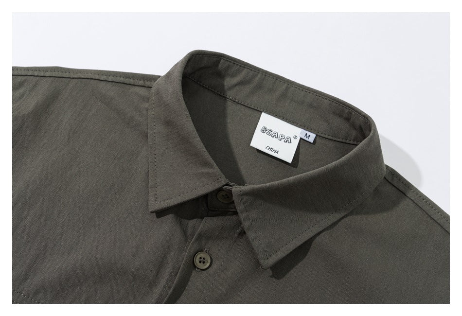 Close-up of an olive-gray short-sleeve shirt collar, buttons, stitching, and neck label.