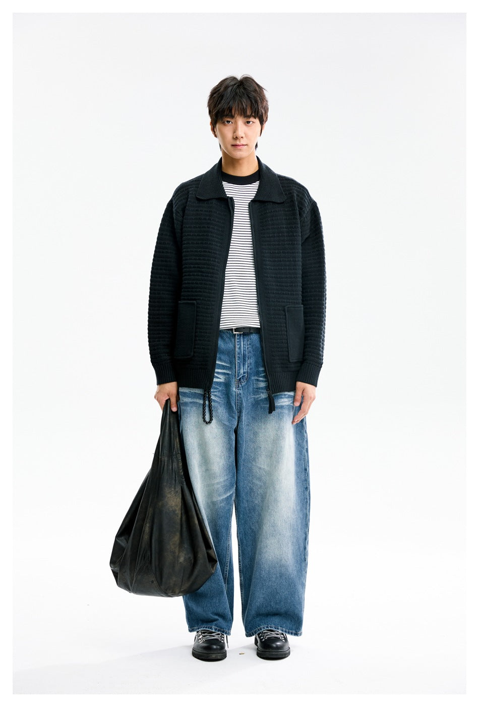 Front view of a model wearing a black textured knit jacket with a wide collar, front zip, ribbed cuffs, and patch pockets.
