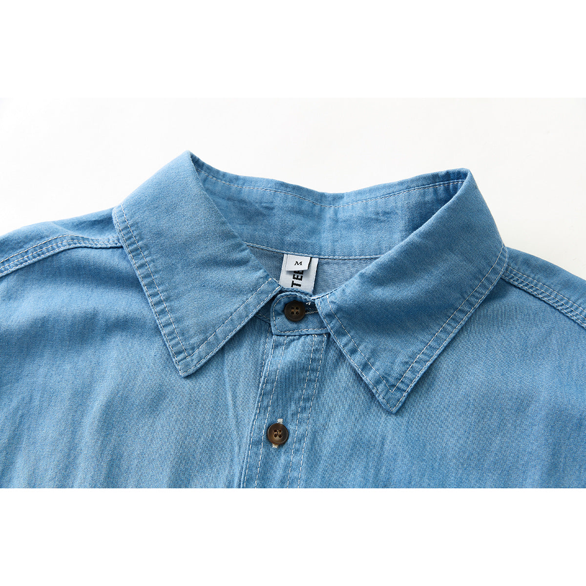 Close-up of a light blue shirt collar, top buttons, and contrast stitching.