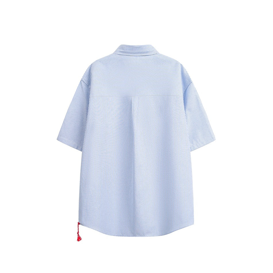 Back view of light blue striped short-sleeve shirt with horizontal-striped yoke and red tassel at hem