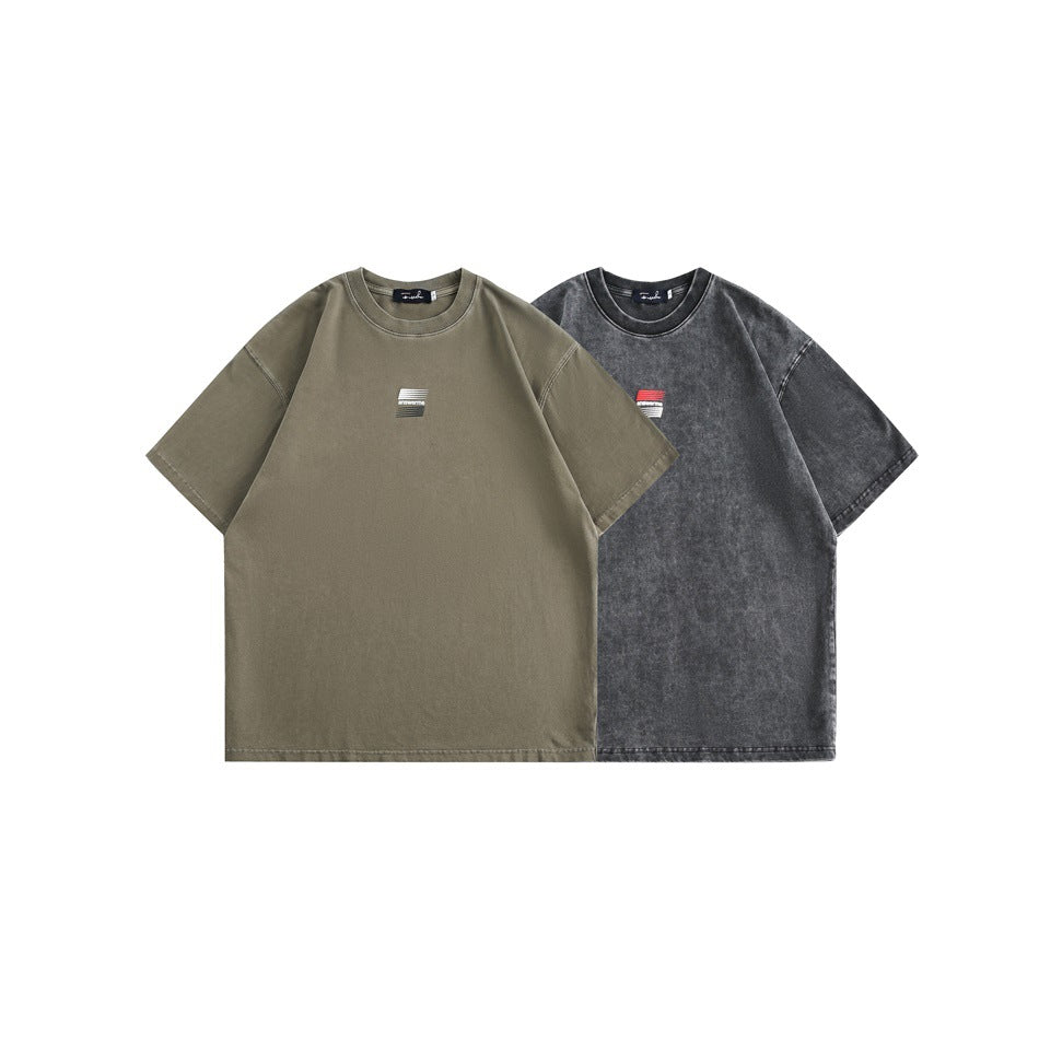 Two front-facing oversized T-shirts shown together in olive taupe and washed charcoal, each with a small chest graphic.