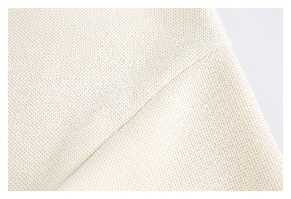 Close-up of ivory textured shirt fabric with a curved stitched seam.