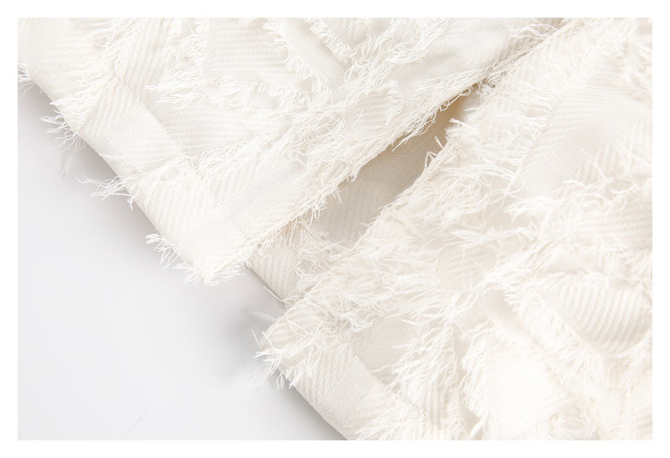 Close-up of overlapping ivory fabric panels with heavily frayed edges and visible diagonal weave.