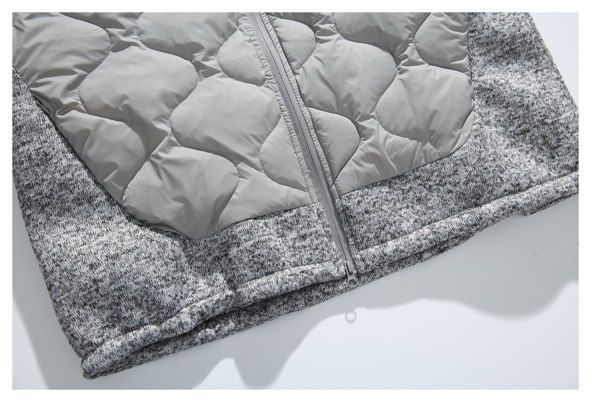 Lower front of a gray jacket showing quilted padding, a marled knit hem, and zipper.