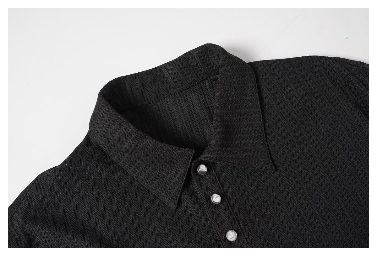 Close-up of a black textured shirt collar and placket with shiny round buttons.